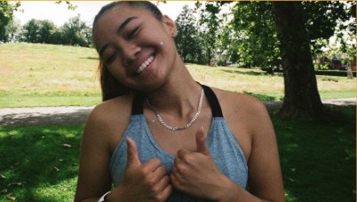 A teenage Alpha Youth guest giving two thumbs up in a park